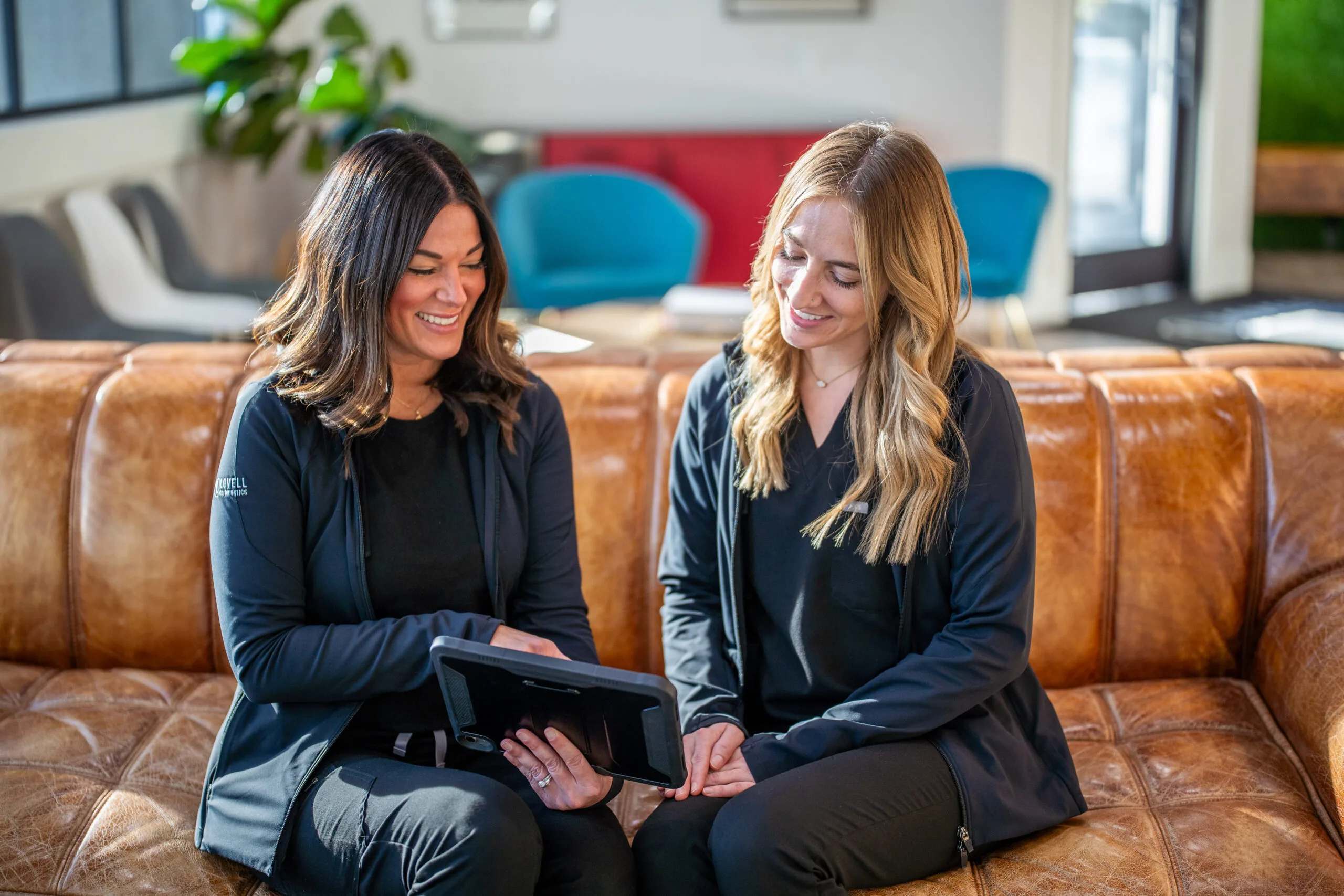 Two staff members at Lovell Orthodontics in Morton & Washington reviewing tablet on couch